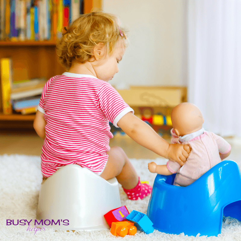 photo of a toddler sitting on the potty chair with a doll.