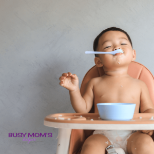 a baby eating food in a high chair with a spoon in his mouth